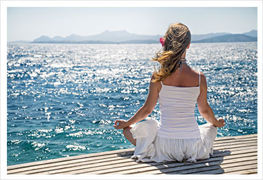 Woman meditating by ocean